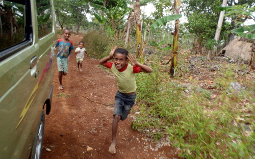 Indonésie západní Timor kluci běží za autem. Tradiční vesnice